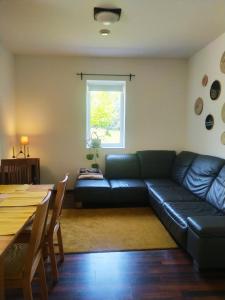 a living room with a black leather couch and a table at Bíbor-lak ökoszálláshely in Pannonhalma +20 photos