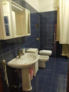a blue tiled bathroom with a sink and two toilets at Appartamento Varese in Varese