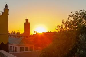 una puesta de sol sobre una ciudad con una torre de reloj en Kahena Lifestyle Concept, en Marrakech