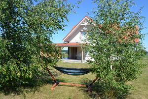 a hammock in front of a house between two trees at Domek mamy in Tykocin