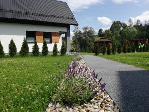 un jardín con flores púrpuras y una casa en Domek nad potokiem, en Grywałd