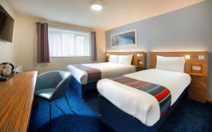 um quarto de hotel com duas camas e uma escrivaninha em Travelodge Dublin Airport North 'Swords' em Swords
