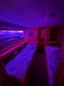 Habitación pequeña con luces moradas y camas. en Riti Yacht, en Kalkara