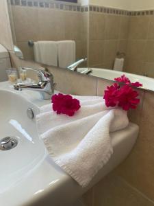 a bathroom sink with a towel with red flowers on it at San Raffaele Guest House in Villasimius +16 photos