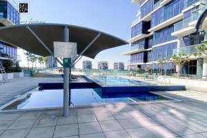 a pool in the middle of a building with an umbrella at Mira Holiday Homes - Spacious Studio with Balcony - Free Wifi in Dubai