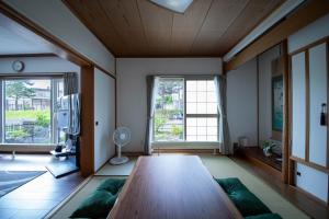 a living room with a wooden table and two windows at The Villa Moiwa in Sapporo