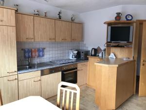 eine kleine Küche mit Holzschränken und einem TV in der Unterkunft Haus Hanser in Zellberg