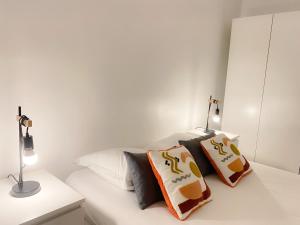 ein weißes Schlafzimmer mit einem Bett mit Kissen darauf in der Unterkunft Le Vauban in Calais