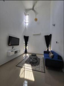 Q Homestay @ Temerloh في تيميرلوه: غرفة معيشة مع أريكة زرقاء وتلفزيون