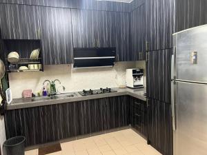 uma cozinha com armários de madeira e um frigorífico de aço inoxidável em Netflix Wifi Homestay Kak Nad Saujana Utama em Sungai Buluh
