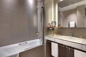 a bathroom with a tub and a sink and a mirror at Splendid Etoile in Paris