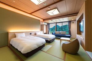 um quarto de hotel com duas camas e um sofá em Ooedo Onsen Monogatari Premium Kinosaki em Toyooka
