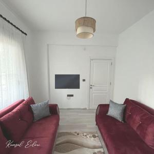 a living room with a red couch and a tv at Kumsal Evleri & Güney - Bahçeli, Denize 200m in Bozyazı