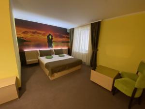 a bedroom with a bed and a painting on the wall at AMBER Hotel & Cafe in Bohorodchany