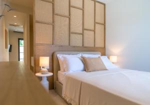 a bedroom with a white bed with a wooden headboard at Argostoli Essence Suites in Argostoli