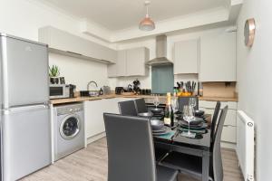 a kitchen with a black table and chairs in a kitchen at Beautiful 3 Bed Apartment - Large Outside Terrace & Parking - The Perfect Choice For Families, Small Groups & Contractors - Close To Ventnor Beach in Ventnor