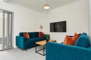 a living room with two blue couches and a tv at Beautiful 3 Bed Apartment - Large Outside Terrace & Parking - The Perfect Choice For Families, Small Groups & Contractors - Close To Ventnor Beach in Ventnor