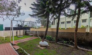 a garden with a swing and trees and a building at Treebo Kodai Kings Park, 650 M From Kodai Lake in Kodaikānāl
