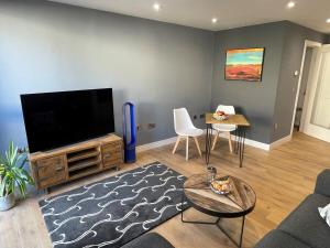 a living room with a flat screen tv and a table at Harbourside Hideaway - Superb Flat with Terrace in Bristol