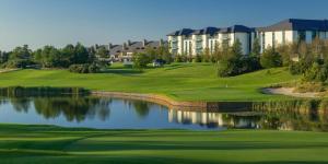 a golf course with a pond in front of a building at Kearney's Cottage B&B in Killenard