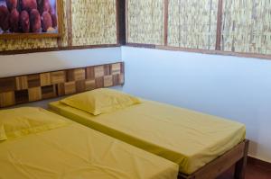 two beds with yellow sheets in a room with windows at Espace Menamasoandro in Morondava