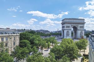an arch in a city with trees and buildings at Splendid Etoile in Paris
