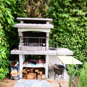 a outdoor brick oven with a table and a chair at NOUVEAUTE 2023 Maison Cocooning avec jardin, Terrasse couverte et Jacuzzi in Bellerive-sur-Allier