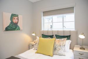 1 dormitorio con 1 cama y una pintura de una mujer en Royal Pearl, Insta-worthy APT en Paarl