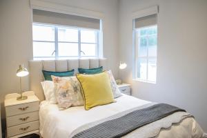ein Schlafzimmer mit einem Bett mit Kissen und einem Fenster in der Unterkunft Royal Pearl, Insta-worthy APT in Paarl