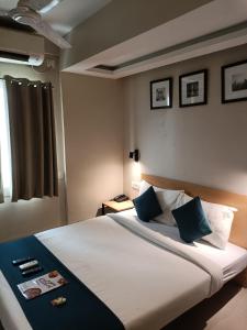a bedroom with a large white bed with blue pillows at Hotel Mayfair Tower in Kolkata
