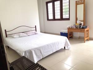 a bedroom with a white bed and a wooden table at Vegan Stay by The Vegan Kitchen by Sulo in Boralesgamuwa