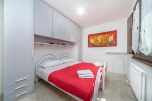 Dormitorio blanco con cama roja y manta roja en Residenza alle Grazie, en Udine