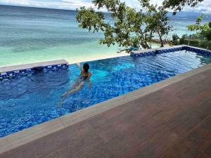 a woman in a swimming pool next to the ocean at The French Villa -Santander in Santander