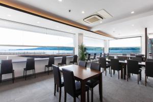 uma sala de jantar com mesas e cadeiras e janelas grandes em Global Resort Misen - グローバルリゾート弥山 em Hatsukaichi