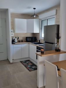 La cuisine est équipée de placards blancs et d'un réfrigérateur en acier inoxydable. dans l'établissement maison cosy avec petit jardin, à Avignon