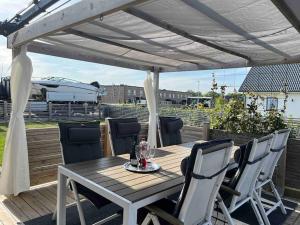 a wooden table and chairs under a white pergola at New luxurious Villa in Helsingborg close to the City in Helsingborg