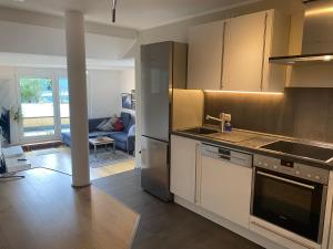 een keuken met witte kasten en een woonkamer bij Moderne CityWohnung nahe Theresienwiese & Westpark in München