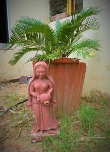Una statua di una bambina in piedi accanto a una pianta in vaso. di Ranthambore Jungle Home a Khilchīpur