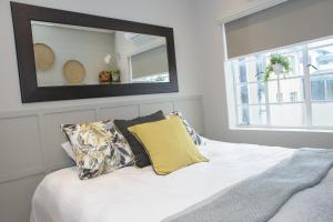 um quarto com uma cama branca e um espelho na parede em Royal Pearl, Insta-worthy APT em Paarl