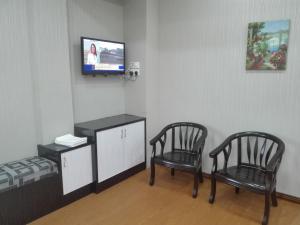 um quarto com duas cadeiras e uma televisão num quarto em Bintang Square Hotel em Kubang Kerian