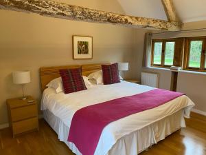 - une chambre avec un grand lit blanc et des oreillers rouges dans l'établissement Hidden cottages, à Henley in Arden