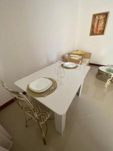 uma mesa branca com pratos e copos em Apartamento Siomaly - Piscina em Praia