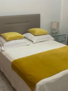 ein Bett mit einer gelben Decke und Kissen darauf in der Unterkunft Apartamento Siomaly - Piscina in Praia