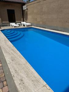 a blue swimming pool with two white chairs next to a building at General guesthouse in Yerevan