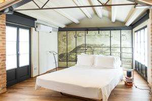 una camera con un grande letto bianco in una stanza con finestre di Palazzo Fauzone Relais a Mondovì