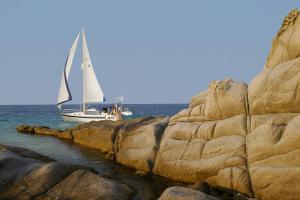 a sail boat on the water next to some rocks at The Diamond of Kriaritsi "Villas with private pools & hydromassage" in Kriaritsi
