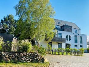 een wit huis met een boom en een hek bij Ferienwohnung Koje 2 in Ostseebad Karlshagen