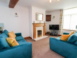 uma sala de estar com dois sofás azuis e uma lareira em 91 Main Street em Frodsham