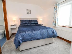 a bedroom with a bed with a blue comforter and a window at 91 Main Street in Frodsham