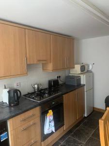 a kitchen with wooden cabinets and a stove top oven at Beautiful 2-Bed House in Larne with free parking in Larne